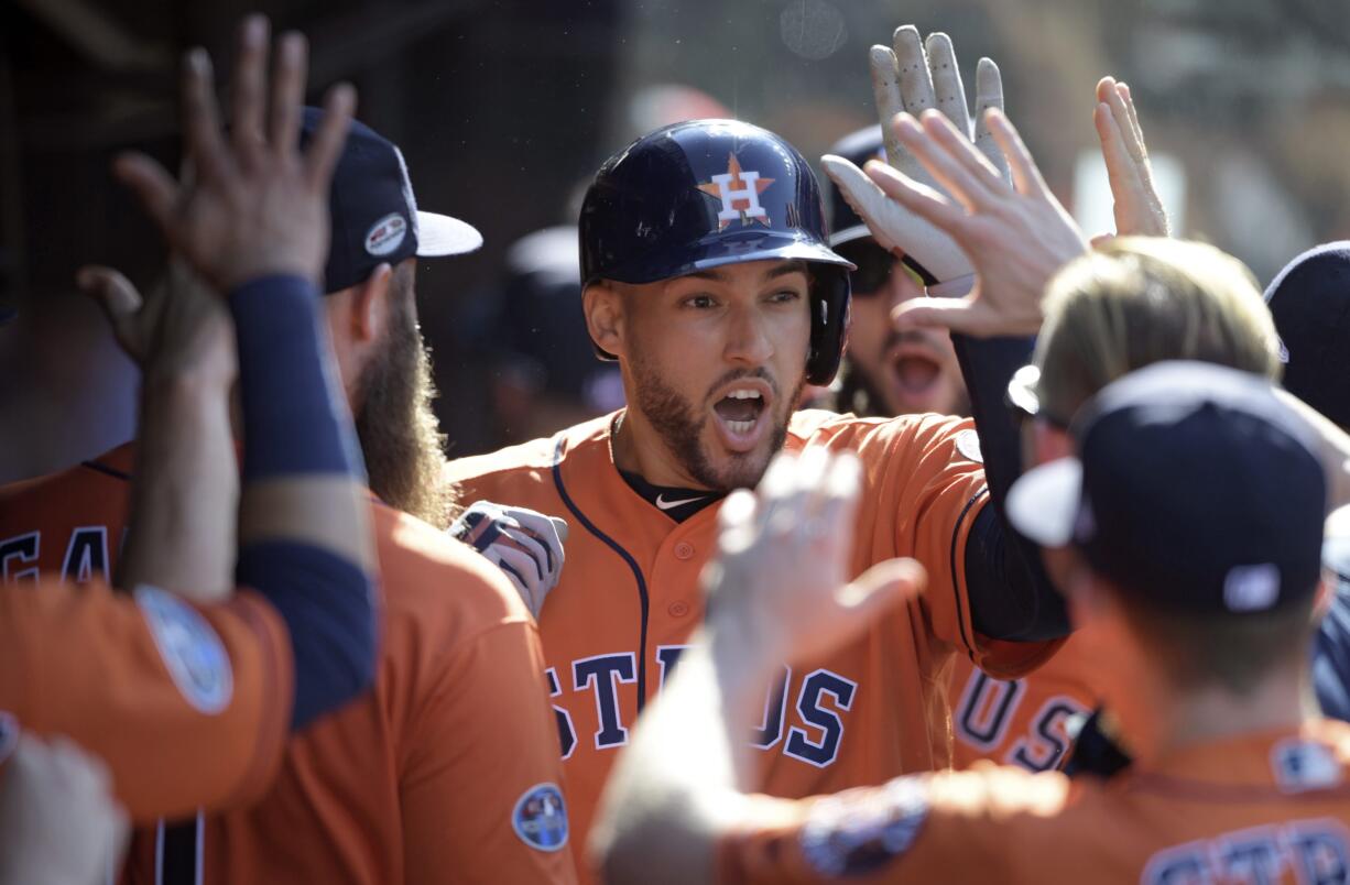 Houston Astros' George Springer is congratulated by teammates after hitting a solo home run off Cleveland Indians starting pitcher Mike Clevinger in the fifth inning during Game 3 of baseball's American League Division Series, Monday, Oct. 8, 2018, in Cleveland.