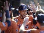 Houston Astros' George Springer is congratulated by teammates after hitting a solo home run off Cleveland Indians starting pitcher Mike Clevinger in the fifth inning during Game 3 of baseball's American League Division Series, Monday, Oct. 8, 2018, in Cleveland.