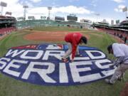 Grounds crew members paint the World Series logo behind home plate at Fenway Park, Sunday, Oct. 21, 2018, in Boston as they prepare for Game 1 of the baseball World Series between the Boston Red Sox and the Los Angeles Dodgers scheduled for Tuesday.