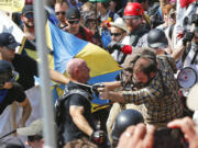 FILE - In this Aug. 12, 2017 file photo, white nationalist demonstrators clash with counter demonstrators at the entrance to Lee Park in Charlottesville, Va. The leader of a Southern California white supremacist group and three other members have been arrested weeks after indictments of other group members for allegedly inciting the riot last year in Charlottesville, Virginia. U.S. Attorney's Office spokesman Thom Mrozek says Rise Above Movement leader Robert Rundo was arrested Sunday at Los Angeles International Airport and is expected in Los Angeles federal court Wednesday, Oct. 24, 2018.