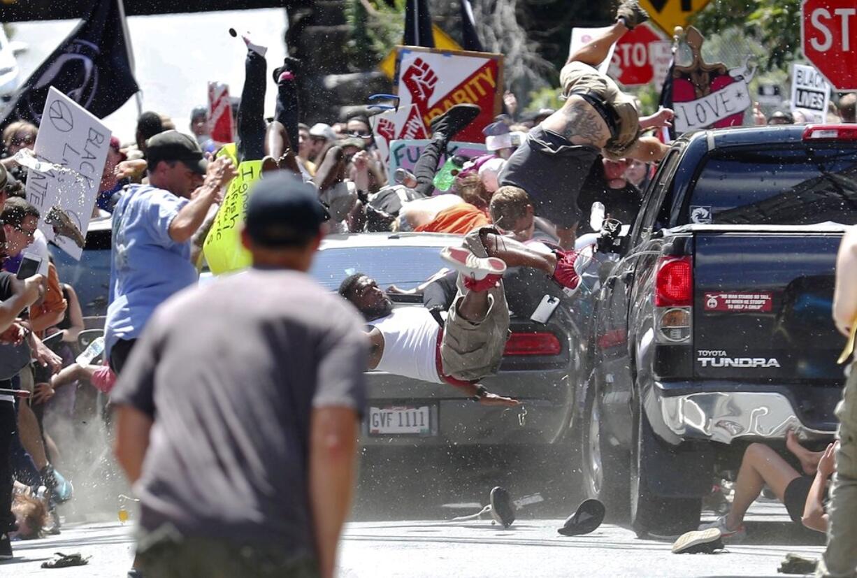 FILE - In this Aug. 12, 2017, file photo, people fly into the air as a vehicle drives into a group of protesters demonstrating against a white nationalist rally in Charlottesville, Va. The leader of a Southern California white supremacist group and three other members have been arrested weeks after indictments of other group members for allegedly inciting the riot last year in Charlottesville, Virginia. U.S. Attorney's Office spokesman Thom Mrozek says Rise Above Movement leader Robert Rundo was arrested Sunday at Los Angeles International Airport and is expected in Los Angeles federal court Wednesday, Oct. 24, 2018. (Ryan M.