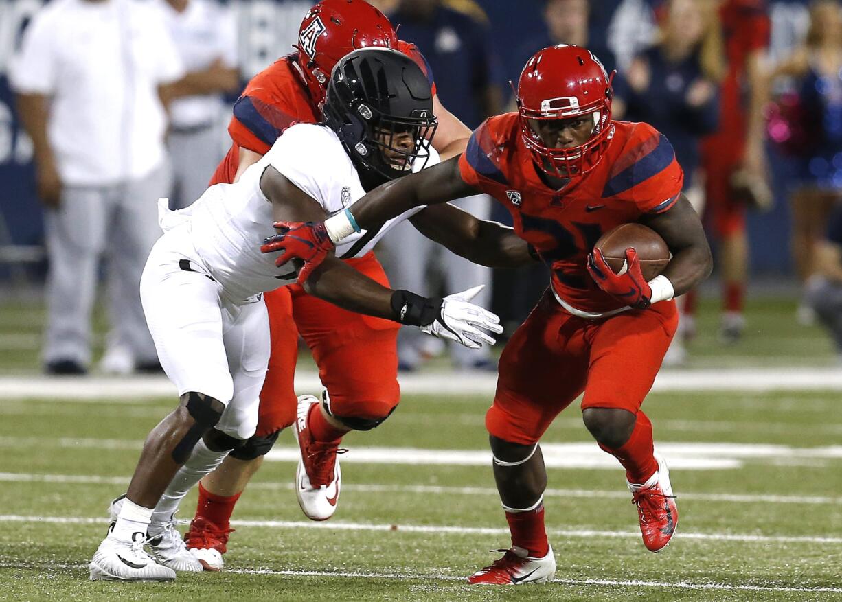 Arizona running back J.J. Taylor (21) stiff arms an Oregon defender in the first half during an NCAA college football game, Saturday, Oct. 27, 2018, in Tucson, Ariz.