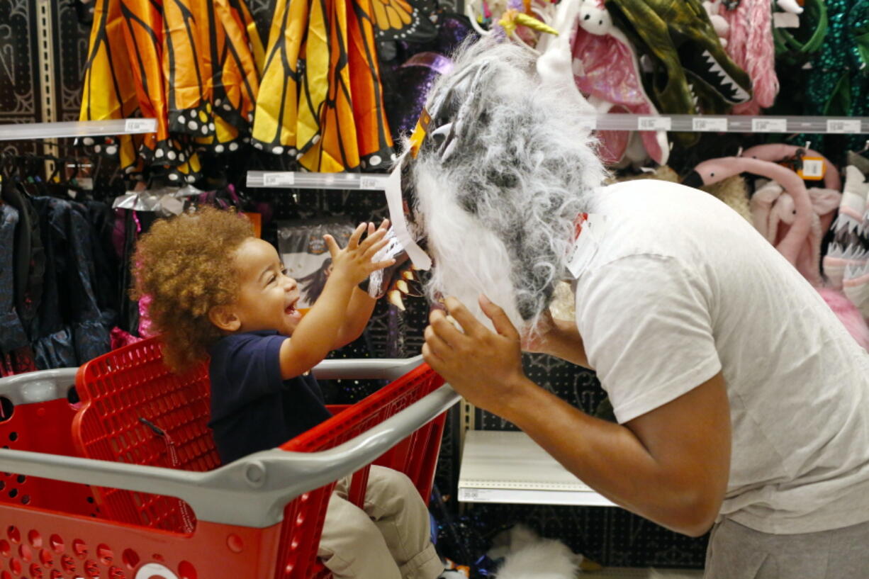 Liam Vasquez, 2, left, and his father, Will Vasquez, try on Halloween masks at a Target department store on Wednesday in Pembroke Pines, Fla. Retailers such as Walmart and Target are expanding their costume offerings and creating designated sections where customers can find more of their Halloween needs in one place.