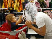 Liam Vasquez, 2, left, and his father, Will Vasquez, try on Halloween masks at a Target department store on Wednesday in Pembroke Pines, Fla. Retailers such as Walmart and Target are expanding their costume offerings and creating designated sections where customers can find more of their Halloween needs in one place.