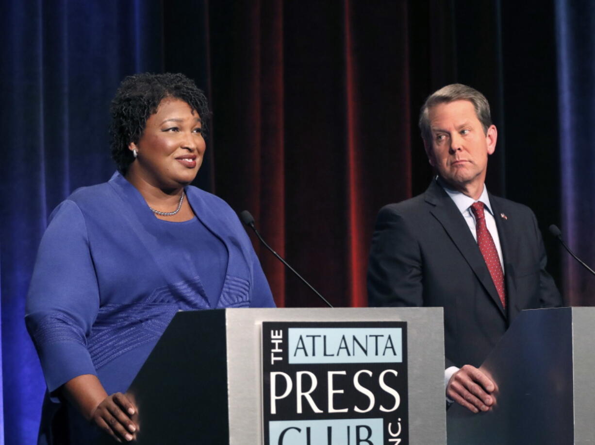 FILE - In this Tuesday, Oct. 23, 2018 file photo, Democratic gubernatorial candidate for Georgia Stacey Abrams, left, speaks as her Republican opponent Secretary of State Brian Kemp looks on during a debate in Atlanta. A federal judge says Georgia election officials must stop rejecting absentee ballots and absentee ballot applications because of a mismatched signature without first giving voters a chance to fix the problem. U.S. District Judge Leigh May on Wednesday, Oct. 24, 2018 ordered the secretary of state’s office to instruct county election officials to stop the practice for the November midterm elections.