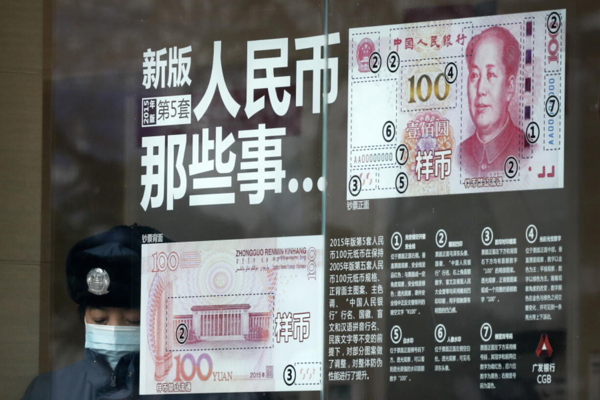 FILE - In this file photo taken Sunday, Jan. 1, 2017, a security guard wearing a protection mask against air pollution takes a rest near a bank window panel displaying the security markers on the latest Yuan note in Beijing. China’s government on Tuesday, Oct. 9, 2018 promised not to weaken its currency to boost exports and rejected U.S. concern about the sagging yuan as groundless and irresponsible.