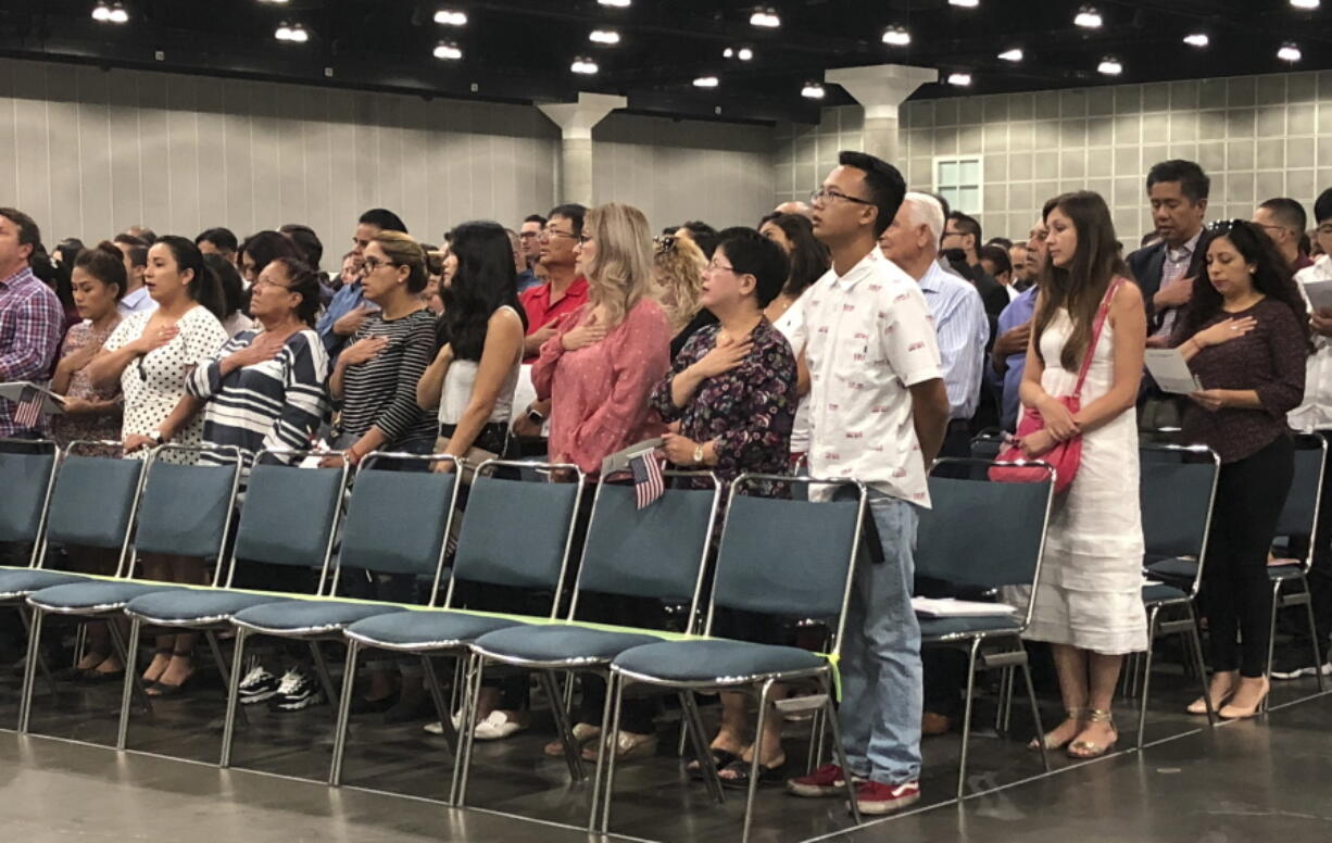 In this Sept. 18, 2018 photo new American citizens stand during a naturalization ceremony in Los Angeles. More than 700,000 immigrants are waiting on their applications to become U.S. citizens, a process that in many parts of the country now takes a year or more. The number of aspiring Americans surged during 2016, jumping 27 percent from a year ago as Donald Trump made cracking down on immigration a central point of his presidential campaign.