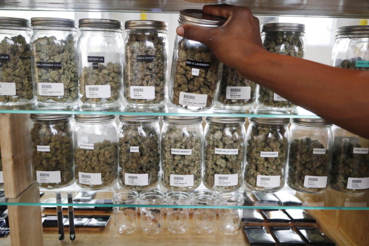 A clerk reaches for a container of marijuana buds for a customer at Utopia Gardens, a medical marijuana dispensary, in Detroit. Michigan and North Dakota, where voters previously authorized medical marijuana, will decide now if the drug should be legal for any adult 21 and older. They would become the 10th and 11th states to legalize so-called recreational marijuana since 2012.