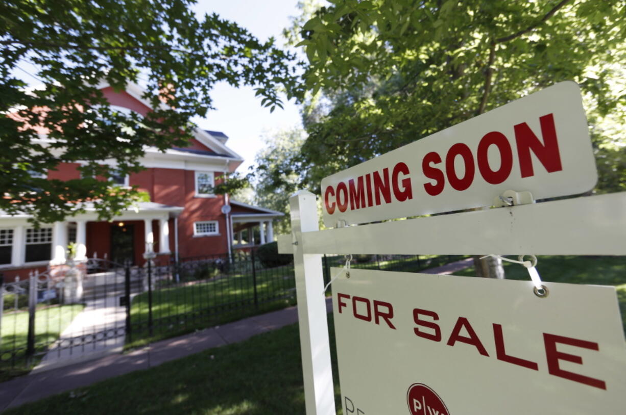 A sale signs stand outside a home on the market in Denver.