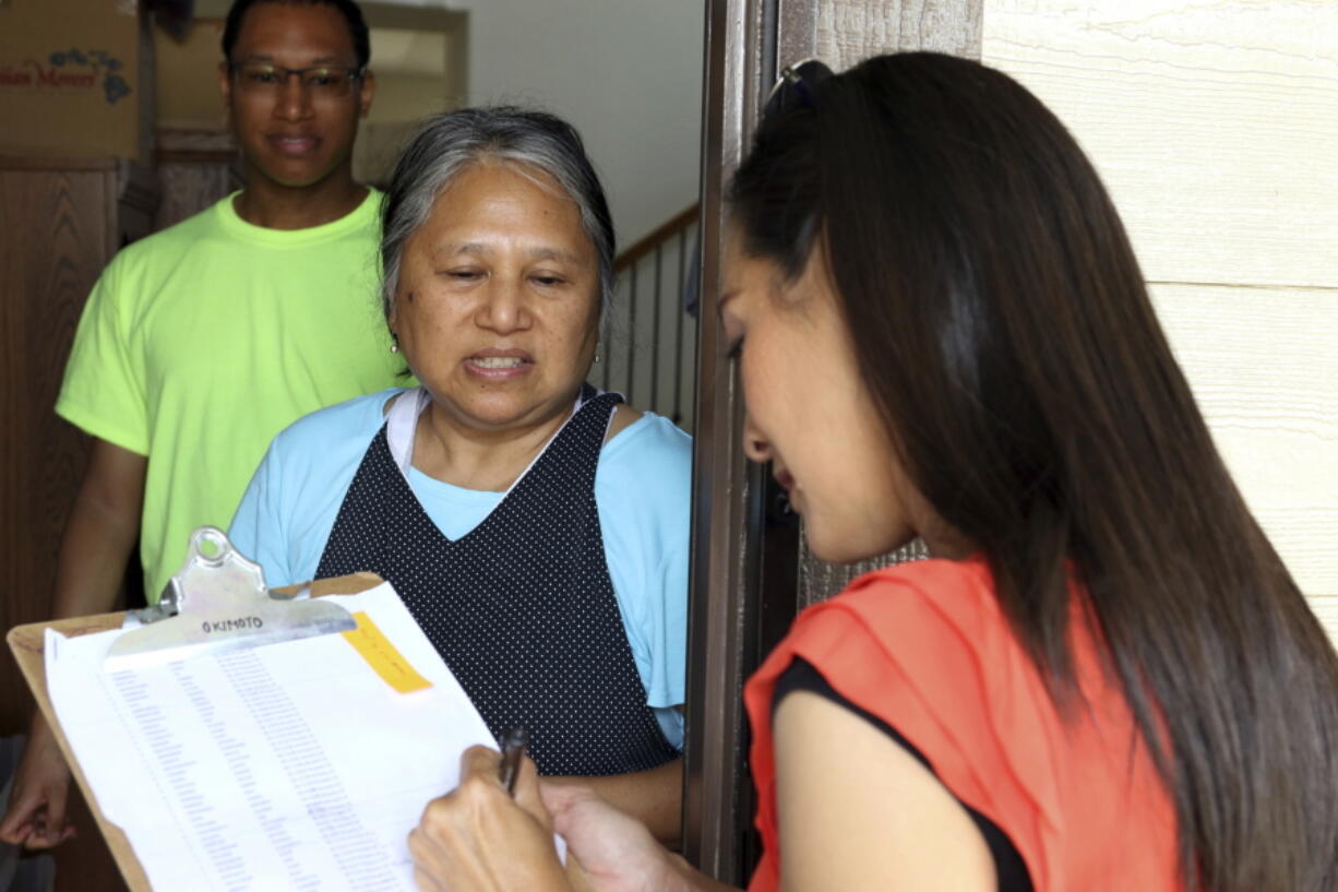 Val Okimoto, right, a candidate to represent the Honolulu suburb of Mililani in the state House, speaks to voter Corazon Faxon, middle, and Faxon’s son Matthew Faxon, left, as she walks door-to-door in Mililani, Hawaii. Hawaii’s Republican Party has just five representatives in the 51-member state House.