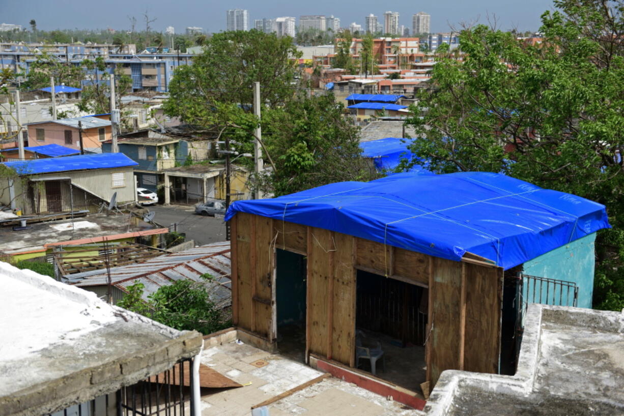 Homes in the Cantera area are covered with FEMA tarps, where buildings from the Hato Rey area stand in the background in San Juan, Puerto Rico. A new law requires the Federal Emergency Management Agency to investigate how it came to award Hurricane Maria relief contracts to a company with an unproven record. The Associated Press reported last year that the newly-formed contractor, Florida-based Bronze Star, LLC, won more than $30 million in FEMA contracts but never delivered the emergency tarps and plastic sheeting for repairs of damaged homes in Puerto Rico.