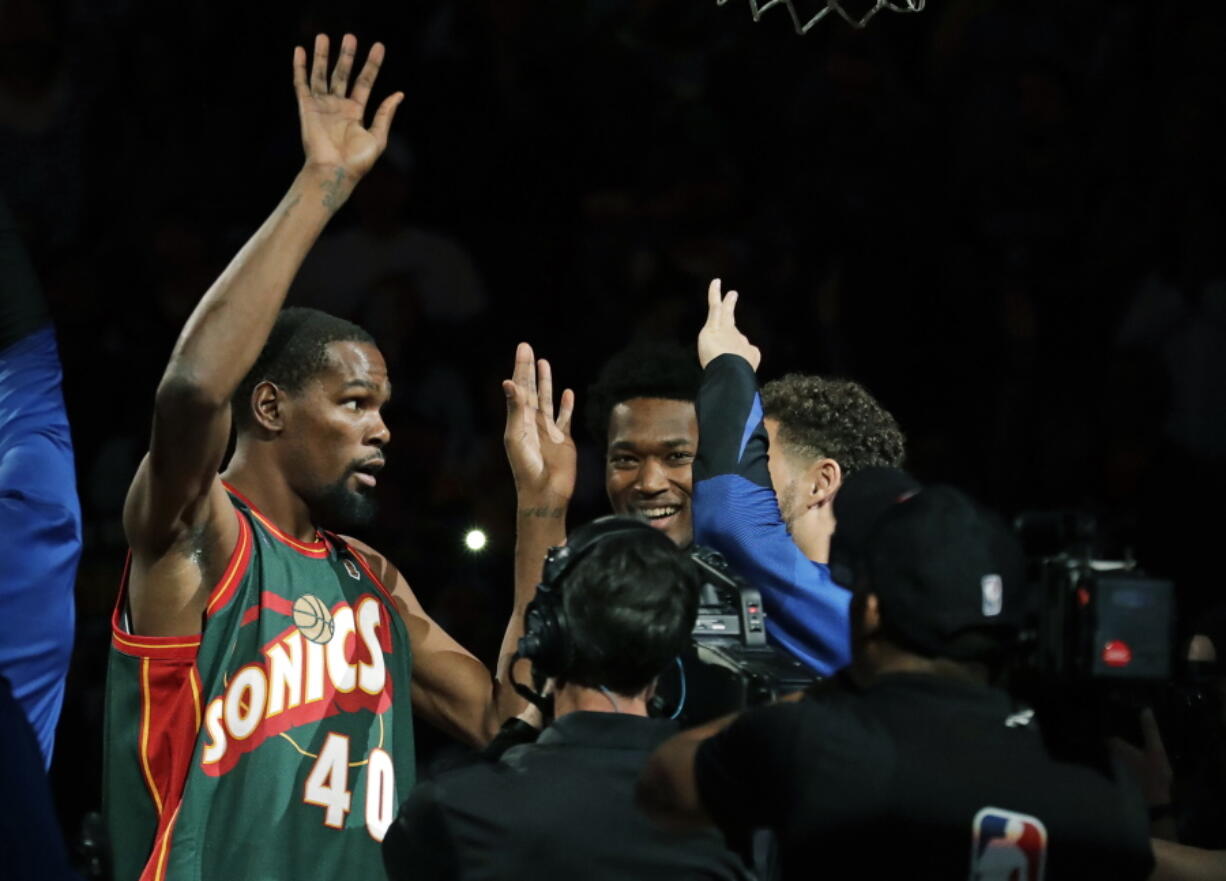 Golden State Warriors forward Kevin Durant, left, appears during player introductions wearing the jersey of Seattle SuperSonics great Shawn Kemp as he greets teammates before an NBA basketball preseason game against the Sacramento Kings, Friday, Oct. 5, 2018, in Seattle. (AP Photo/Ted S.