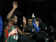 Golden State Warriors forward Kevin Durant, left, appears during player introductions wearing the jersey of Seattle SuperSonics great Shawn Kemp as he greets teammates before an NBA basketball preseason game against the Sacramento Kings, Friday, Oct. 5, 2018, in Seattle. (AP Photo/Ted S.