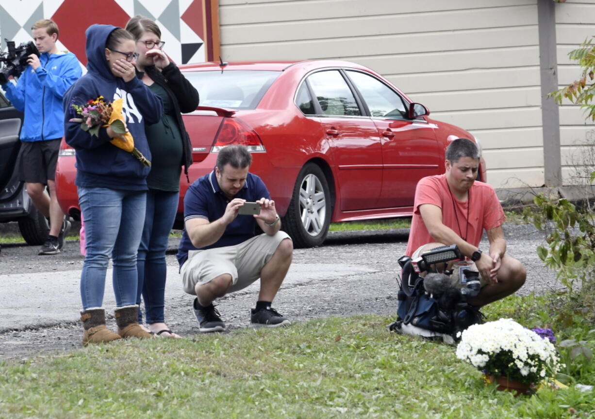 People place flowers Sunday at the scene where 20 people died as the result of a limousine crashing into a parked and unoccupied SUV at an intersection a day earlier, in Schoharie, N.Y.