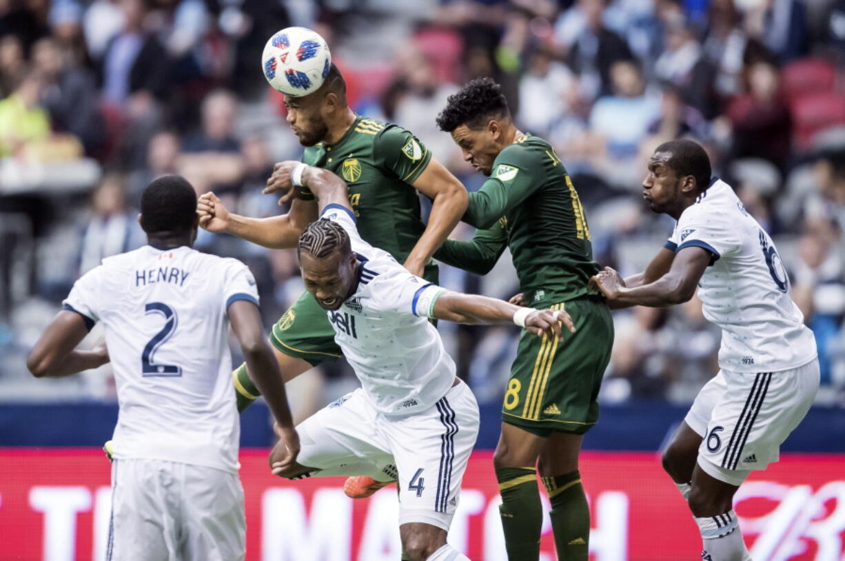 Portland Timbers' Bill Tuiloma, back left, gets his head on the ball in front of teammate Julio Cascante, second from right, as Vancouver Whitecaps' Kendall Waston (4), Ali Ghazal (66) and Doneil Henry (2) defend during the first half of an MLS soccer game in Vancouver, British Columbia, Sunday, Oct. 28, 2018.