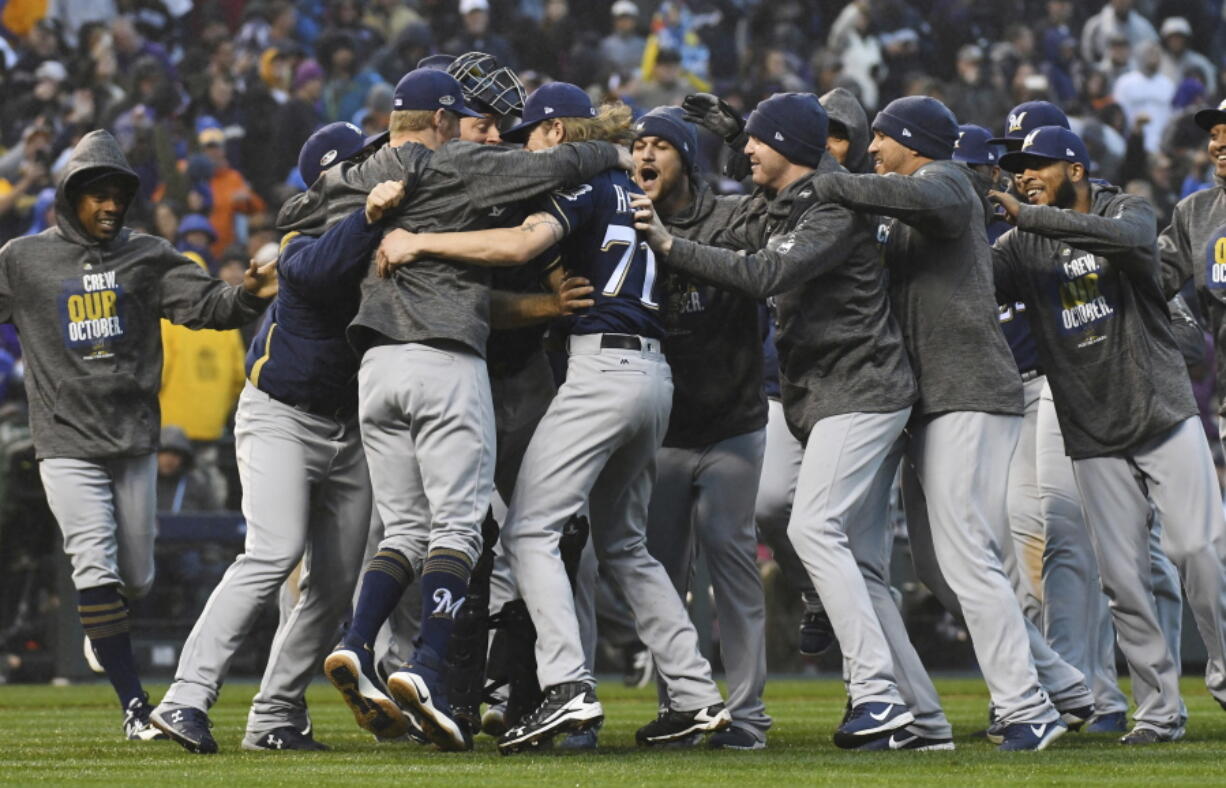 Milwaukee Brewers celebrate after the final out by the Colorado Rockies in the ninth inning of Game 3 of a baseball National League Division Series Sunday, Oct. 7, 2018, in Denver. The Brewers won 6-0 to sweep the series in three games and move on to the National League Championship Series.