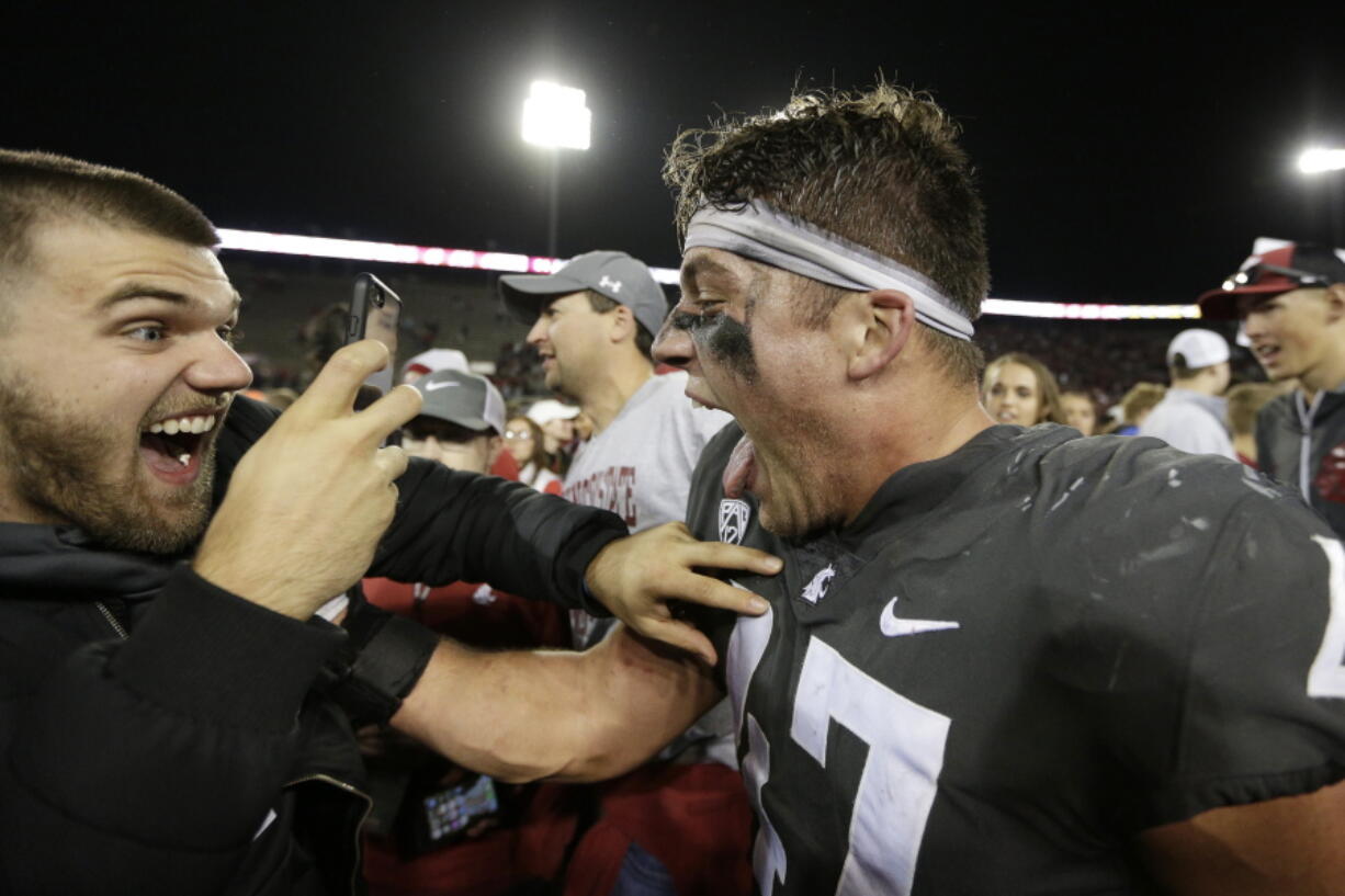 Washington State linebacker Peyton Pelluer, right, celebrates with a fan after his team won an NCAA college football game 34-20 against Oregon, in Pullman, Wash., Saturday, Oct. 20, 2018.