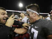 Washington State linebacker Peyton Pelluer, right, celebrates with a fan after his team won an NCAA college football game 34-20 against Oregon, in Pullman, Wash., Saturday, Oct. 20, 2018.