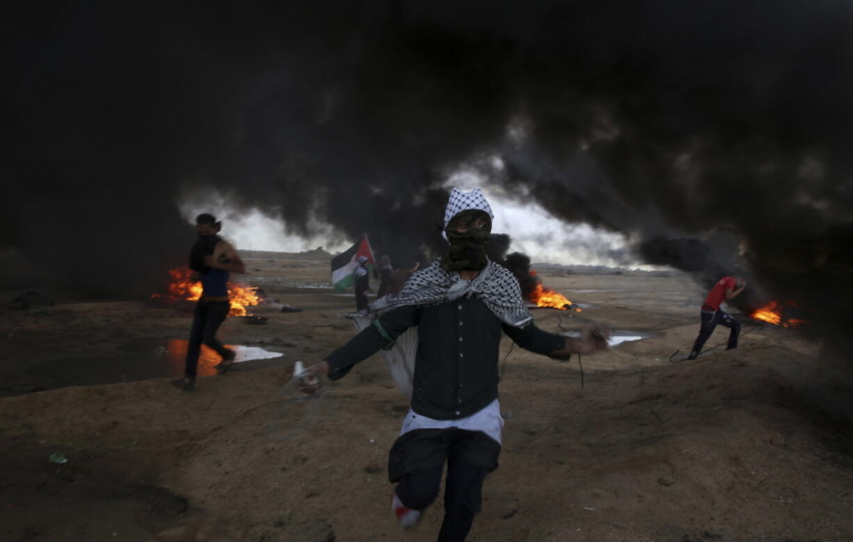 Protesters run when burn tires near the fence of the Gaza Strip border with Israel during a protest east of east of Gaza City, Friday, Oct. 26, 2018.