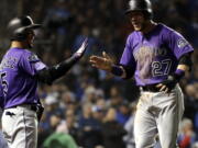 Colorado Rockies’ Trevor Story, right, celebrates with Carlos Gonzalez after scoring the go-ahead run on a hit by Tony Wolters in the 13th inning against the Chicago Cubs. Nam Y.