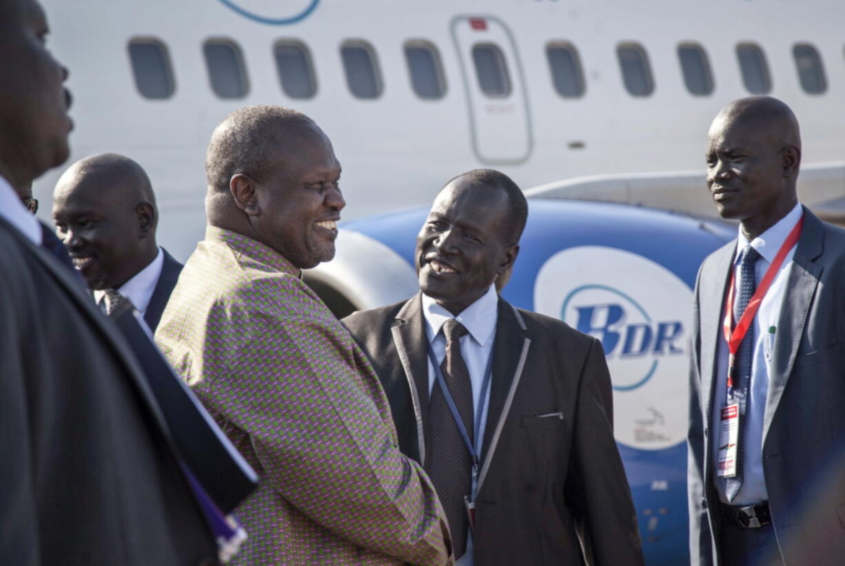 South Sudan’s opposition leader Riek Machar, center-left, is greeted as he arrives at the airport in Juba, South Sudan, on Wednesday. For the first time since fleeing the war-torn country more than two years ago, Machar returned on Wednesday to take part in a nationwide peace celebration.