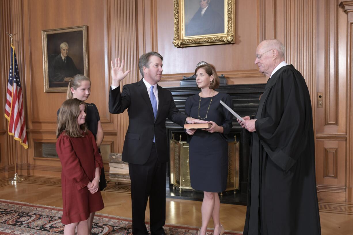 Retired Justice Anthony M. Kennedy, right, administers the Judicial Oath to Judge Brett Kavanaugh in the Justices' Conference Room of the Supreme Court Building. Ashley Kavanaugh holds the Bible. At left are their daughters, Margaret, background, and Liza.