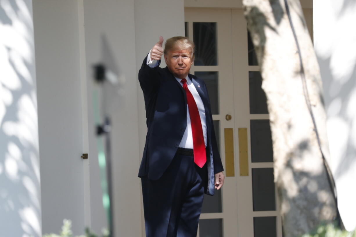 President Donald Trump gives a thumbs up to the media as he walks along the colonnade near the Rose Garden of the White House in Washington on Monday.