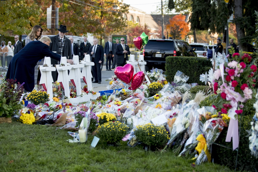 President Donald Trump, accompanied by first lady Melania Trump, left, and Tree of Life Rabbi Jeffrey Myers, third from left, places a stone from the White House at a memorial for those killed at the Tree of Life Synagogue in Pittsburgh, Tuesday, Oct. 30, 2018.