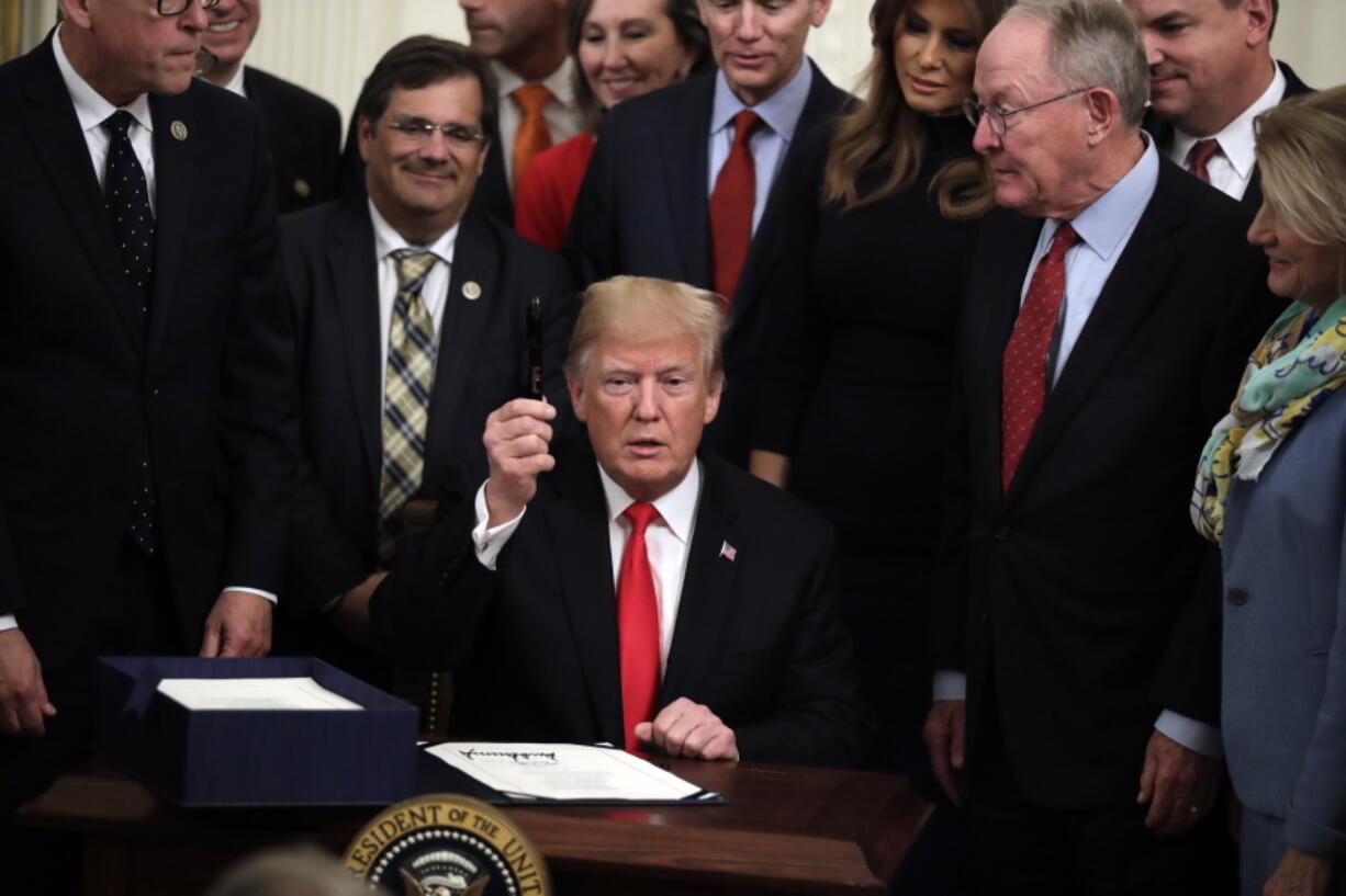President Donald Trump holds up a pen in the East Room of the White House on Wednesday after signing bipartisan legislation to confront the opioid crisis.