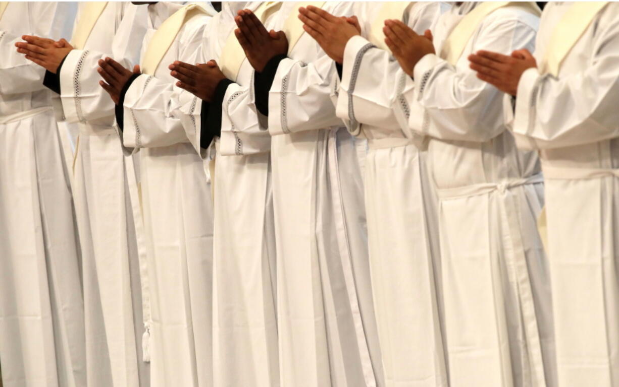 FILE - In this Sunday, April 22, 2018 file photo, priests pray during a ceremony in St. Peter’s Basilica at the Vatican. The umbrella organization of Catholic religious orders in the U.S. is suggesting its members consider voluntarily identifying priests accused of sexual abuse, opening up what could be a major new chapter in the Catholic Church’s long-running abuse and cover-up saga, The Associated Press has learned.