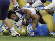 Washington running back Myles Gaskin, top, loses his helmet as he is tackled by UCLA linebacker Lokeni Toailoa (52) during the first half of an NCAA college football game Saturday, Oct. 6, 2018, in Pasadena, Calif.