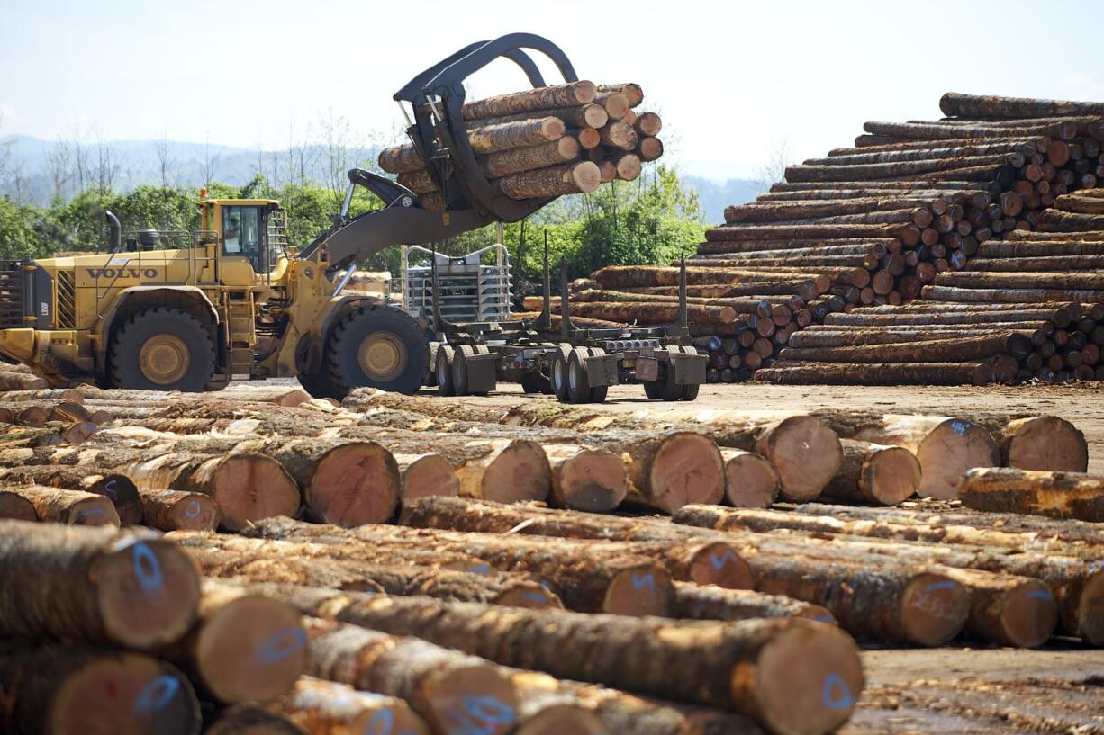 A log loader picks up a load of timber from a truck in a scaling and sorting area at Columbia Vista Corp in 2014.(The Columbian files)