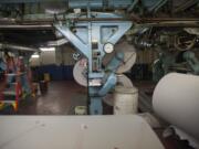 Newsprint arrives on big rolls, which are attached to the underside of The Columbian's Goss Metro offset press.