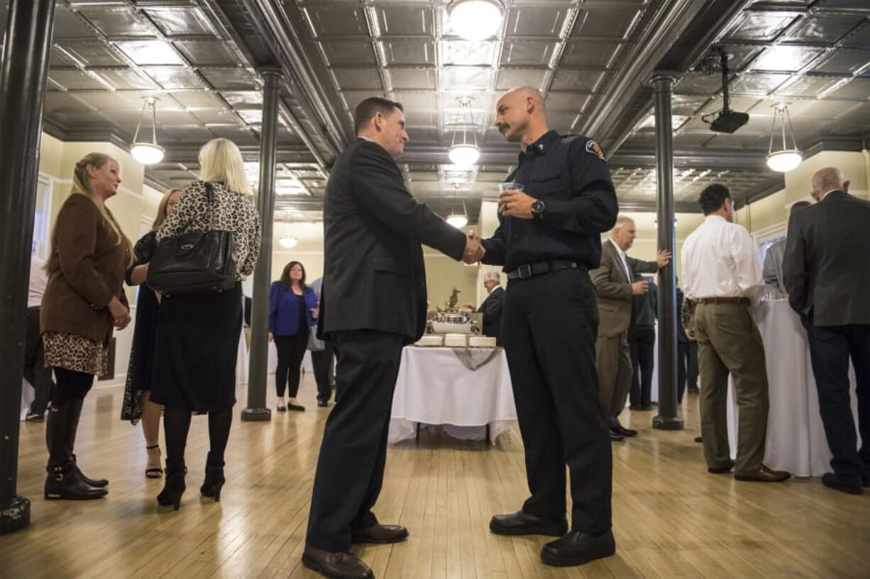 Retired Marine Lt. Col. Robert Darling, left, and Peter Schrater, Vancouver Fire Department chaplain, shake hands during a social hour before the Symbol of Freedom event at the Fort Vancouver Artillery Barracks on Thursday night. Darling is the keynote speaker at this year’s Symbol of Freedom fundraiser for CDM Caregiving Services.