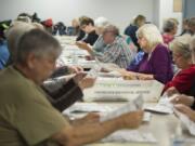 A packed table of election officials including Juanita Berry, wearing purple, sorts through ballots returned so far ahead of the Nov. 6 general election. Auditor Greg Kimsey says a record turnout for a nonpresidential year is possible. At top, stacks of ballots wait to be inspected by officials at the Clark County Elections Office.