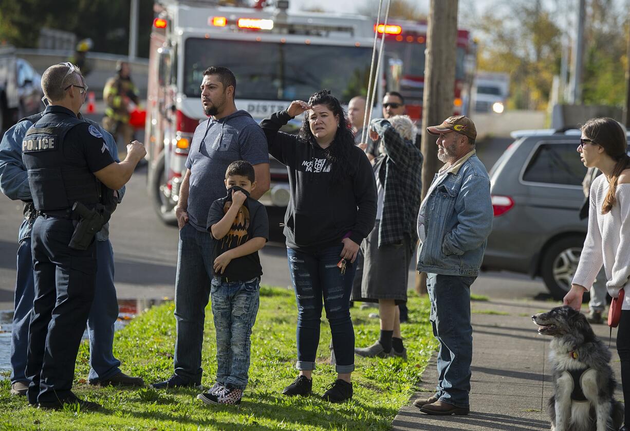 Police talk with bystanders as Vancouver firefighters work at the scene of a house fire at 1105 East 29th Street on Friday afternoon, Nov. 2, 2018. One woman was reportedly severely injured in the blaze.