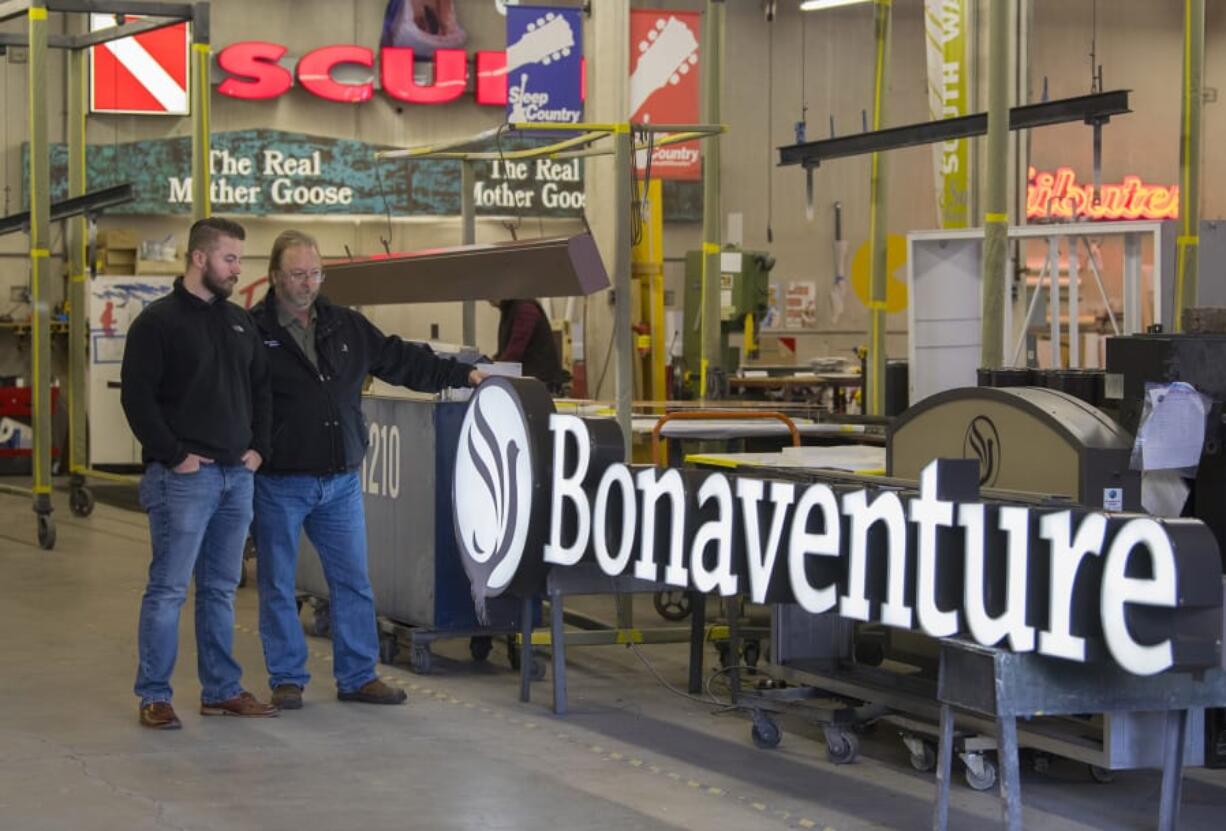 Dylan Taylor, left, and his father, Steve Taylor, check out some of the signs created at Garrett Sign, 811 Harney St., Vancouver. The company, started in 1946, has created signs for many types of businesses, from local mom-and-pop shops to chains with faraway locations.