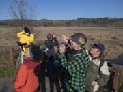 Laura Whittemore, in green plaid, looks for birds with Steigerwald Lake National Wildlife Refuge volunteer Margaret Trenholm while leading visitors at the refuge Sunday afternoon. Whittemore was leading a class on birds of prey for birdwatchers.