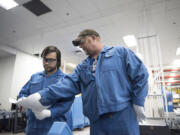 Nathaniel Salveta, left, takes direction from process technician Randall Chromey at Shin-Etsu Handotai (SEH) America on Wednesday afternoon. Salveta is enrolled in the Manufacturing Career Launch program, which will allow him to pursue a degree in mechatronics while working at SEH America.