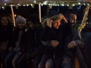 Ellie Russo of Redmond, Ore., 6, right, sits with her dad, Michael Russo of Vancouver, far right, as they ride on a horse-drawn carriage before the annual tree lighting ceremony Friday evening at Esther Short Park in Vancouver. Mill Creek Carriages gave rides around the park throughout the evening.