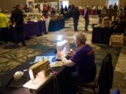 Carol Frana sews reusable gift bags out of recycled fabrics while people shop at the Vancouver Holiday Market at the Hilton Vancouver Washington on Sunday. Volunteers from Repair Clark County, a DIY fix-it group, made the bags, as a means and inspiration to limit personal waste during the holiday season.