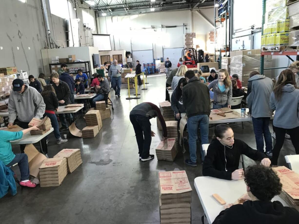 Volunteers fold thousands of donation bags on Nov. 17 at the Clark County Food Bank’s headquarters and warehouse in Vancouver to prepare for the annual Walk & Knock food drive on Saturday.