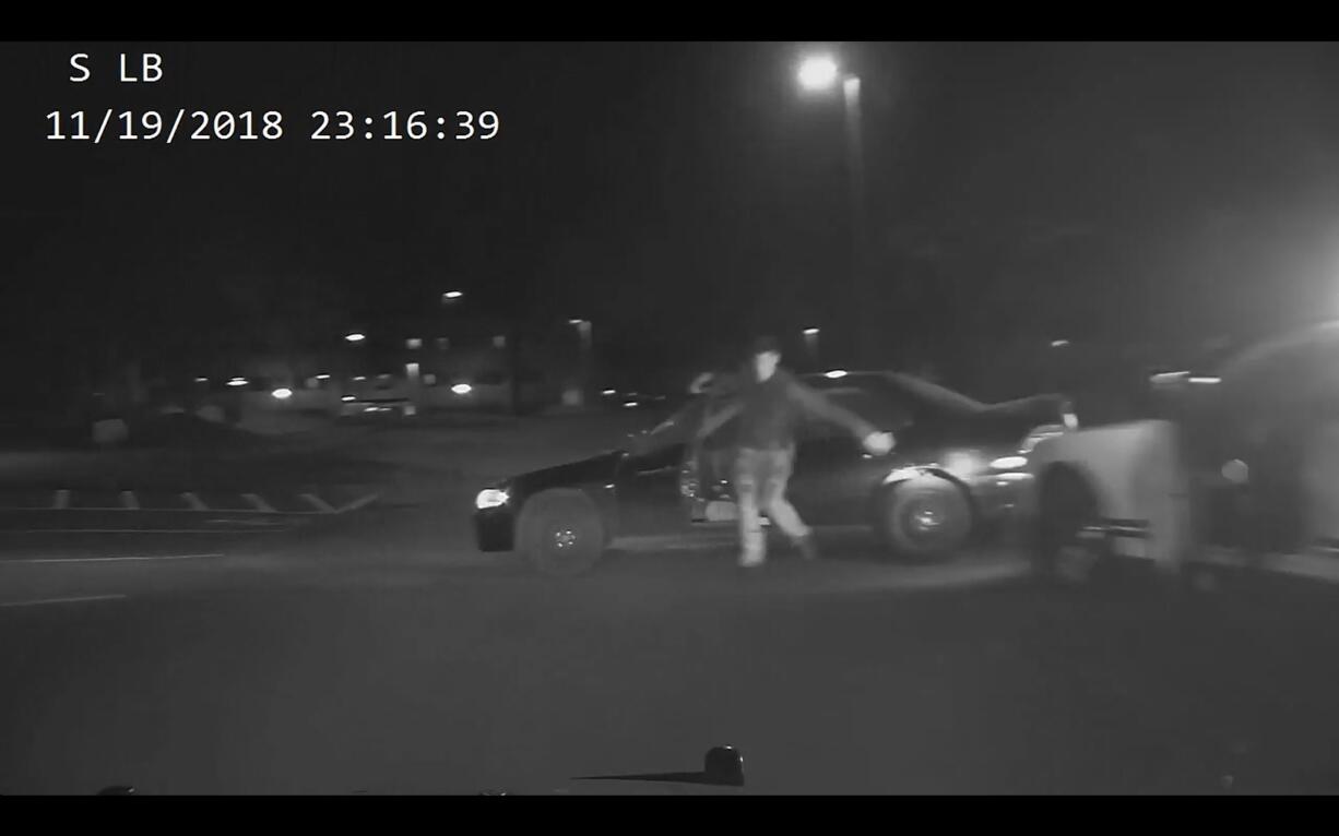 A still from a police car's dash camera video shows a suspect in a pursuit, Isaiah Gellatly of Vancouver, climb out of his moving vehicle while fleeing pursuing police officers Monday night in Happy Valley, Ore. Gellatly's leg was pinned under one of the car's tires, and he was arrested and brought to a hospital with a broken leg once officials got him out.