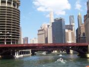 You get a bottom-up view of the Chicago skyline, with streets, sidewalks and pedestrians, all above the cruise boats on the low-lying Chicago River in Chicago.