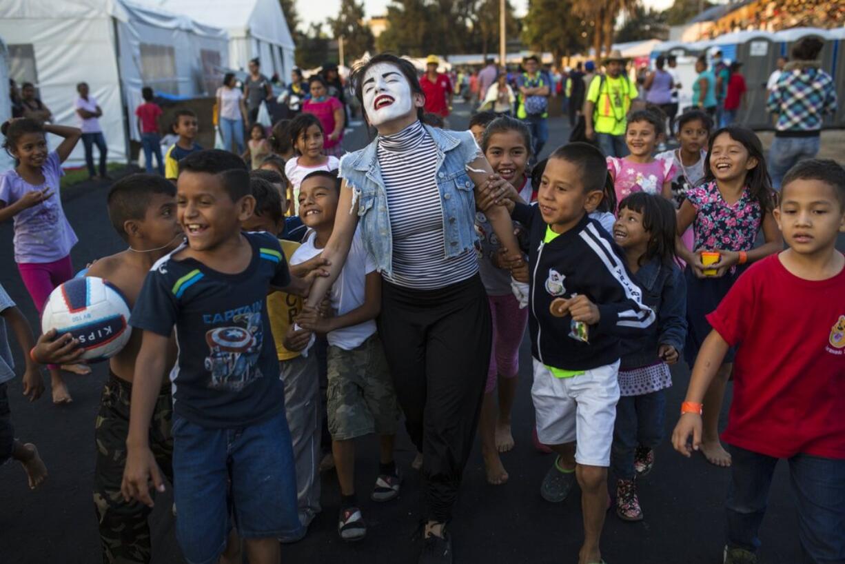 A woman performs as a mime for Central American migrant children at the Jesus Martinez stadium in Mexico City, Tuesday, Nov. 6, 2018. Humanitarian aid converged around the stadium in Mexico City where thousands of Central American migrants winding their way toward the United States were resting Tuesday after an arduous trek that has taken them through three countries in three weeks.