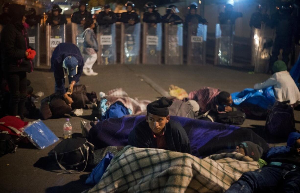 A migrant get ready to spend the night in front of a line of Mexican police in riot gear at the Chaparral border crossing in Tijuana, Mexico, Thursday, Nov. 22, 2018. A small group of Central American migrants marched peacefully to a border crossing in Tijuana Thursday to demand better conditions and push to enter the U.S.