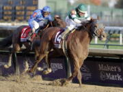 Joel Rosario (14) rides Accelerate to victory as Christophe Soumillon follows on Thunder Snow in the Breeders' Cup Classic horse race at Churchill Downs, Saturday, Nov. 3, 2018, in Louisville, Ky.