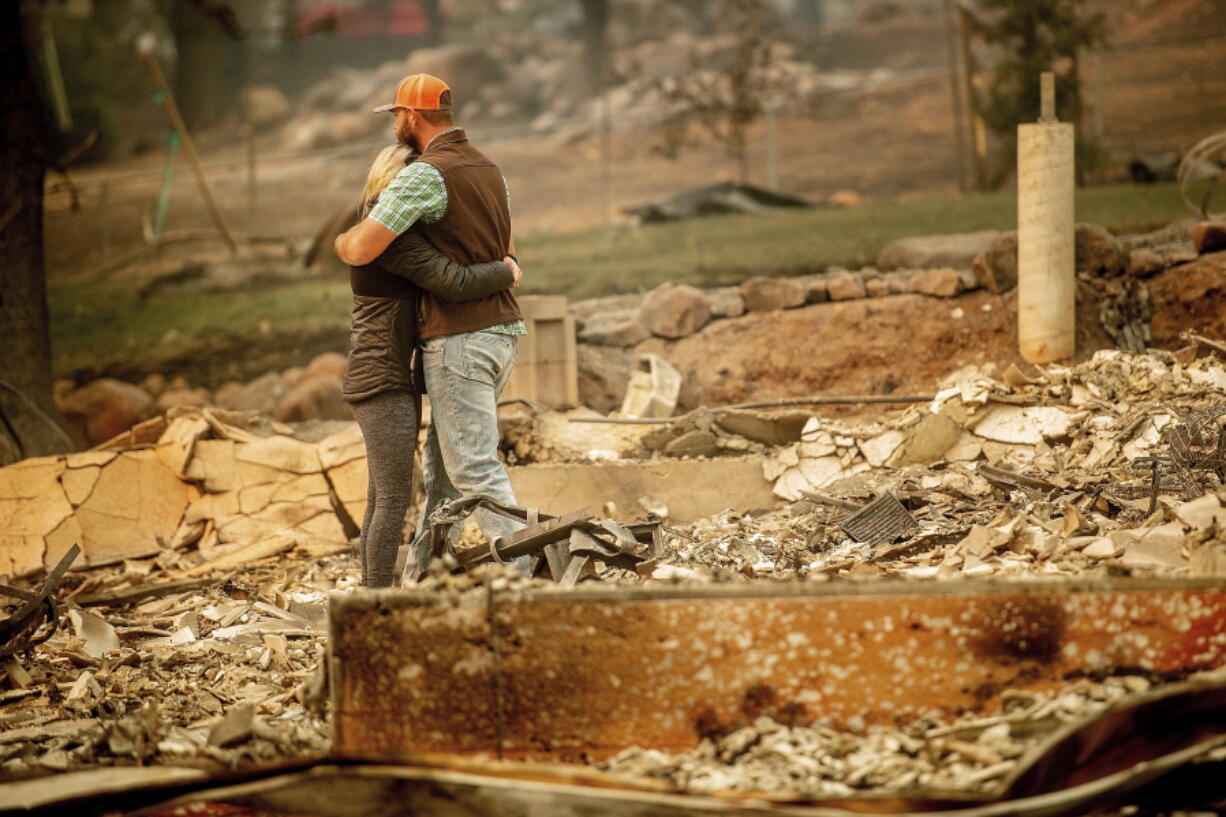 Chris and Nancy Brown embrace while searching through the remains of their home, leveled by the Camp Fire, Monday in Paradise, Calif. As the fire approached, Nancy Brown escaped with her 2-year-old and three dogs.