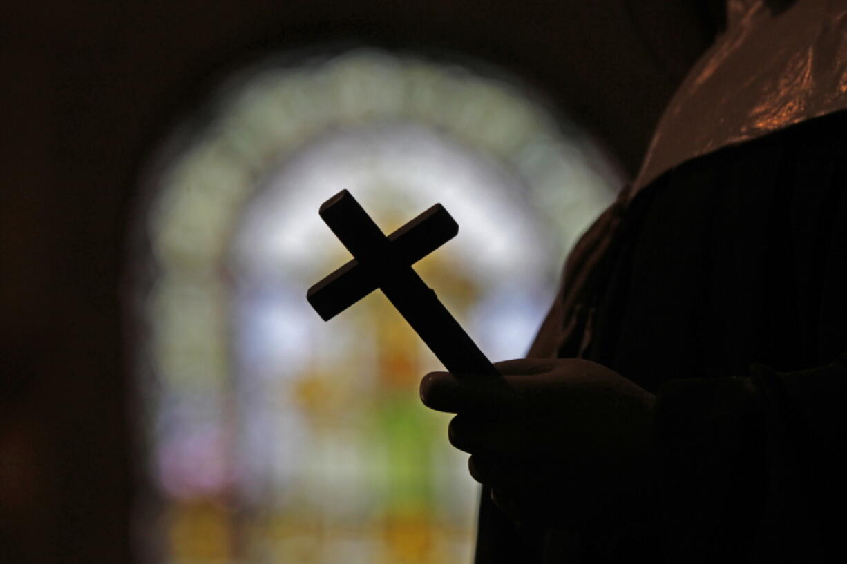 This Dec. 1, 2012, file photo shows a silhouette of a crucifix and a stained glass window inside a Catholic Church in New Orleans. As U.S. Catholic bishops gather for an important national assembly, the clergy sex abuse crisis dominates their agenda.