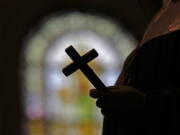 This Dec. 1, 2012, file photo shows a silhouette of a crucifix and a stained glass window inside a Catholic Church in New Orleans. As U.S. Catholic bishops gather for an important national assembly, the clergy sex abuse crisis dominates their agenda.